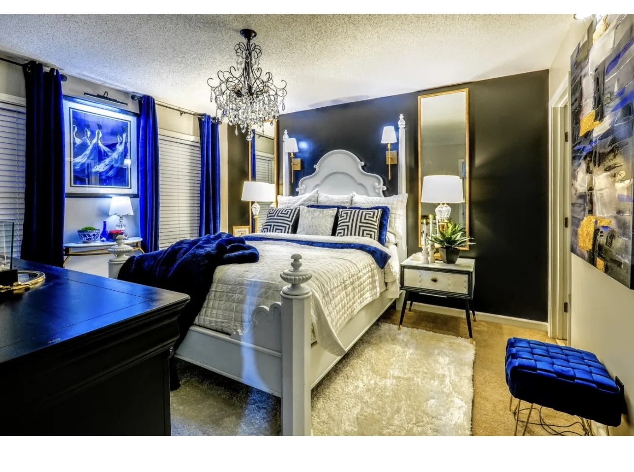 Blue and black bedroom with layered bedding and chandelier
