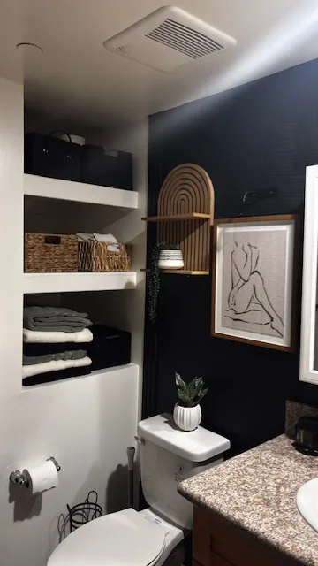 Styled powder room with dark accent wall and open shelving